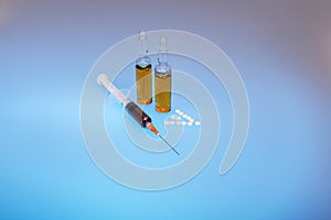 On a blue background, a syringe and two bottles of injections photo